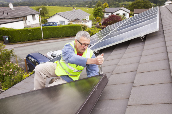 A workman fitting solar thermal panels for heating water, to a house roof in Ambleside, Cumbria, UK, that already has solar PV for generating electricity. © Global Warming Images / WWF-Canon