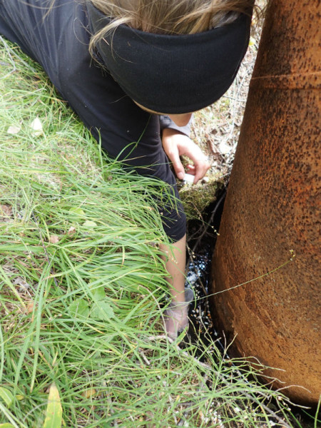 Collecting samples from a 30+ year old pipe protruding from the ground. © Aimee Guile 