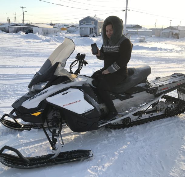 La gestionnaire de la patrouille d'ours polaires à Whale Cove, montre le dispositif de capture des données assise sur une motoneige.