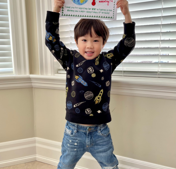 Cameron holding up a picture of the earth and a fundraising thermometer