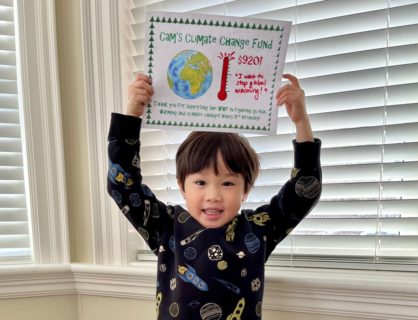 Cameron holding up a picture of the earth and a fundraising thermometer