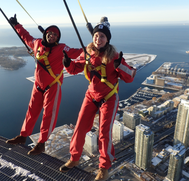 Emily Giles and comedian Jean Paul lean back on the EdgeWalk.