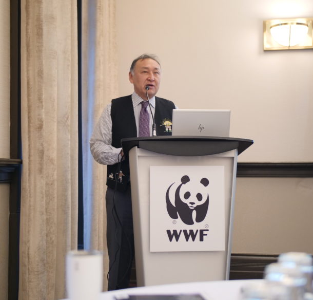 Inuit man standing behind a podium with a WWF panda logo on it