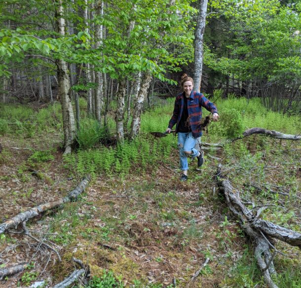 Woman walking through a forest about to plant a tree