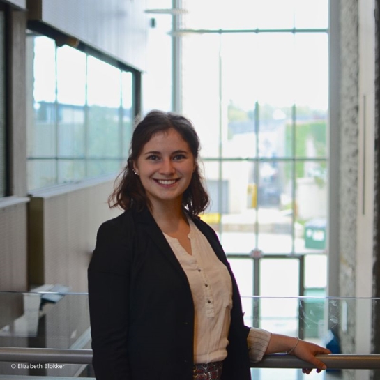 Newly certified Living Planet Leader Elizabeth Blokker smiles while standing on a landing in a university building.