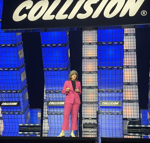 Woman stands on stage that says Collision in the background