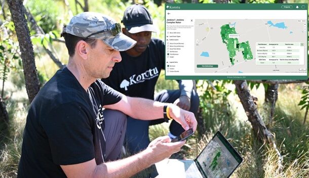 two men looking at a computer in the field