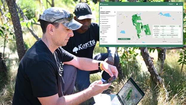 two men looking at a computer in the field