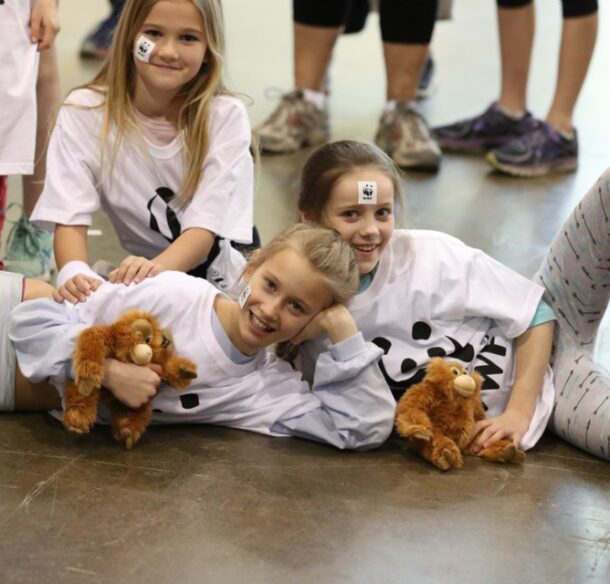 Three children pose in WWF climb T-shirts with adoption kits