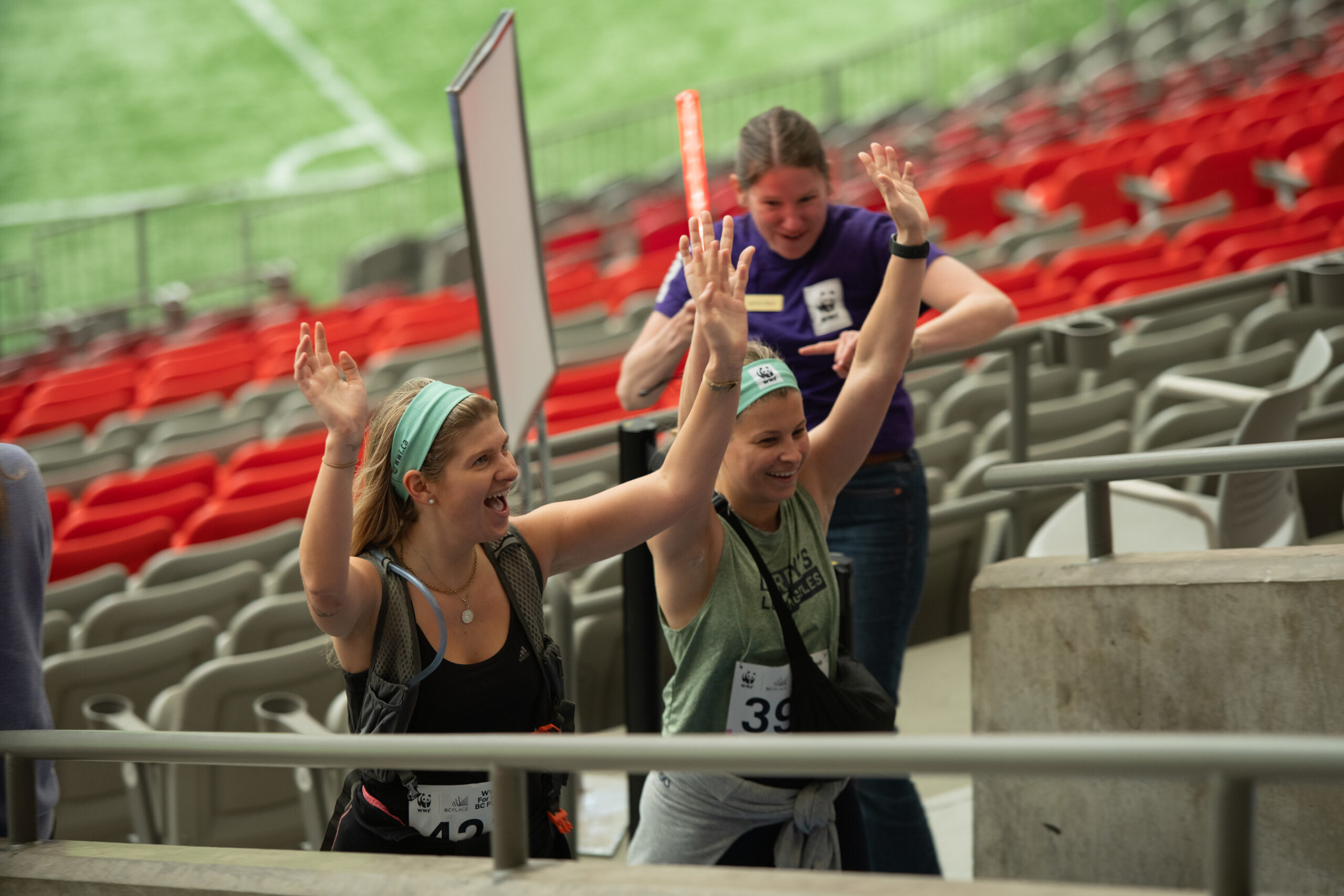 Two women climbing the BC Place stadium stands being cheered on by a WWF-Canada staffer for the Climb for Nature