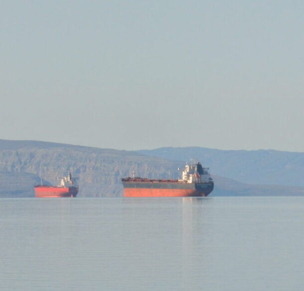 Ore carrier ships in Arctic with land in distant background