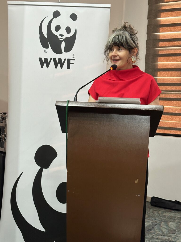 Woman at a podium with a WWF panda logo behind her